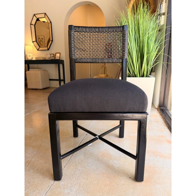 Contemporary coastal dining chair featuring a sleek black wood frame paired with a woven cane back for a sophisticated...