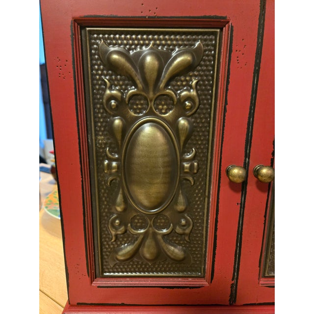This Vintage Distressed Red Cabinet With Metal Design Doors Giving a Rustic Appeal. The metal doors add a touch of Antique...