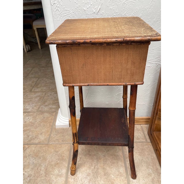 An Antique English sewing table featuring a woven top and lower shelf surface with a rich bamboo rattan structure. A...