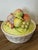 The image shows a vintage ceramic lidded bowl featuring a woven basket-weave base and a lid piled high with sculpted 3D...
