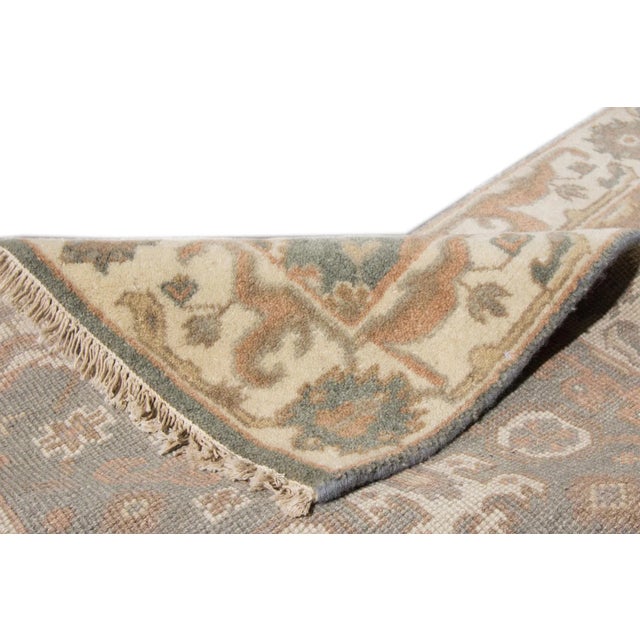Beautiful modern Oushak Style hand-knotted wool runner with a green field. This piece has peach, beige, and tan accents in...