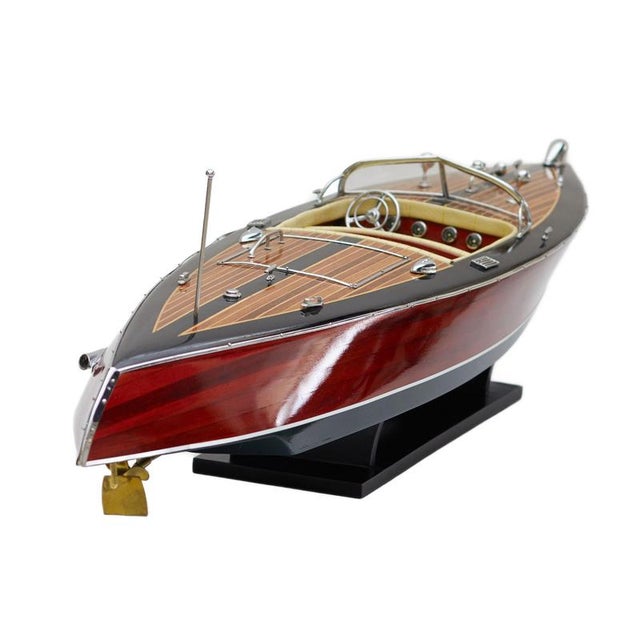 An elegant decorative model of a speedboat crafted from solid wood and fine veneers. The hull is defined by a refined,...