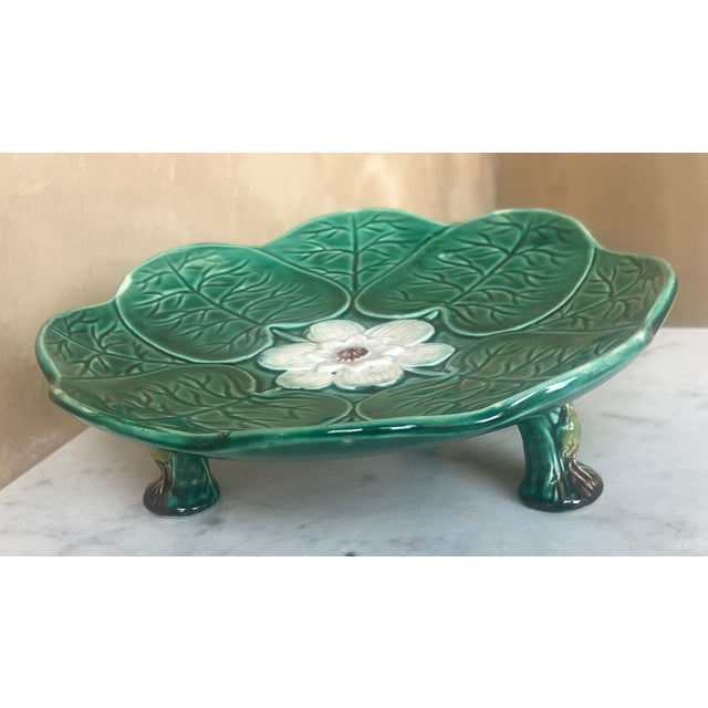 Late 19th century English majolica stand or compote covered in lily pads with a blue flower in the center on three legs...