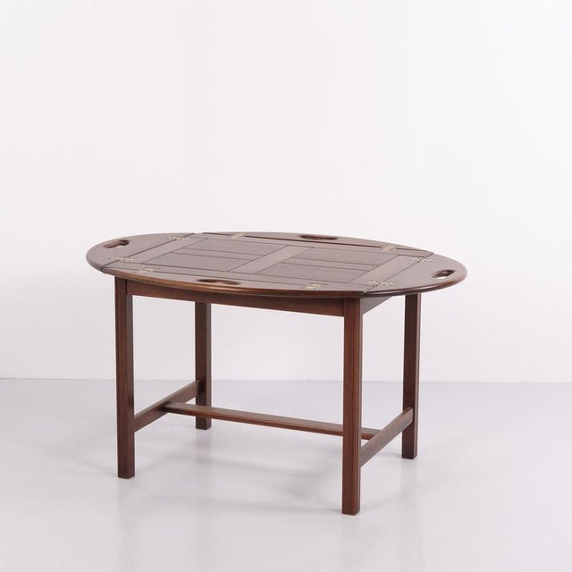 Butler coffee table crafted in polished mahogany with brass fittings. Dating from around the 1940s, the table has a...