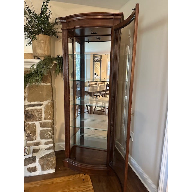 This is Victorian walnut and glass illuminated curio cabinet from Jasper Cabinet Company.. This piece has a mirrored back...
