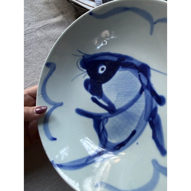 This vintage Chinese porcelain serving bowl features a boldly hand-painted koi fish motif rendered in rich navy blue...