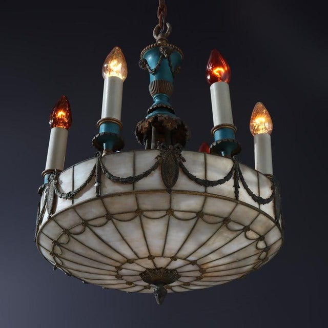 An antique chandelier from circa 1920, embodying a blend of Classical and Arts & Crafts design aesthetics. It features a...