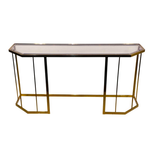 Chic brass plated and beveled and tinted glass console table executed in the Hollywood Regency style, circa 1970/80's. The...