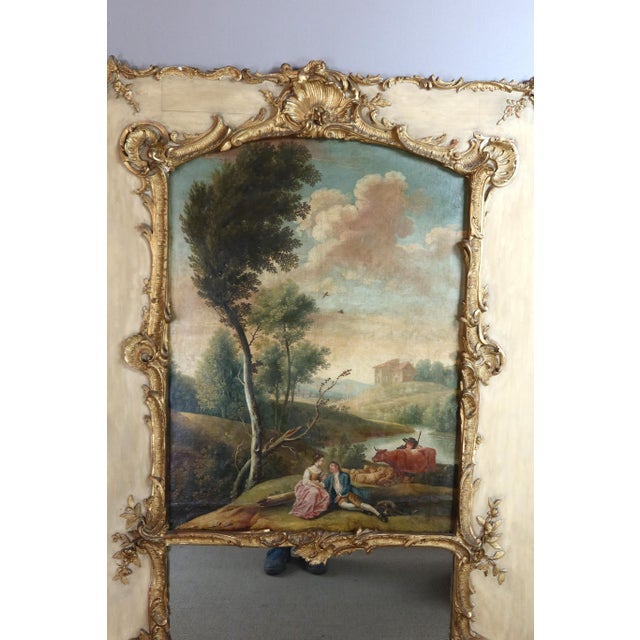Large overmantel mirror in lacquered and gilded wood. The rectangular mirror is topped with an oil painting depicting a...