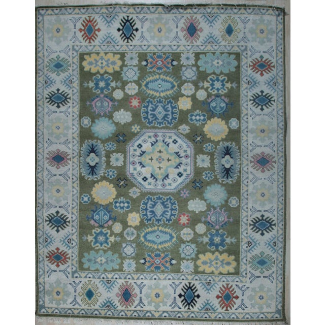 A hand-knotted wool rug in the Kazak tradition, made in India and measuring 10' x 14'. Kazak design is built on bold...