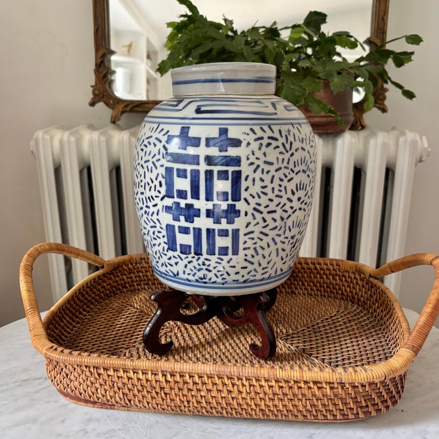 Chinese hand-painted ceramic double happiness ginger jar in blue and white with lid. Dark wood stand gives it height and ....