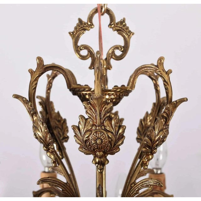 Richly decorated chandelier made of polished brass in the rococo style. Restored electrical installation - ready to use....
