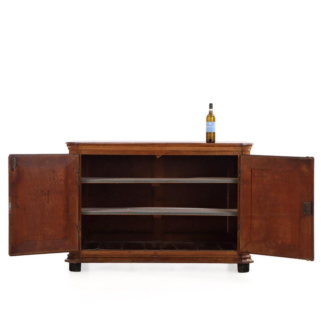 Featuring a shaped top above carved paneled doors and an elegantly scalloped apron, this piece rests on short stile form...