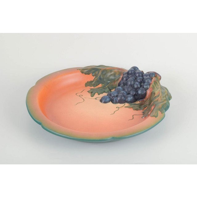 Ipsens Enke Decorative wall dish with grape motif, ca. 1920s/30s. Round glazed ceramic plate featuring a naturalistically...