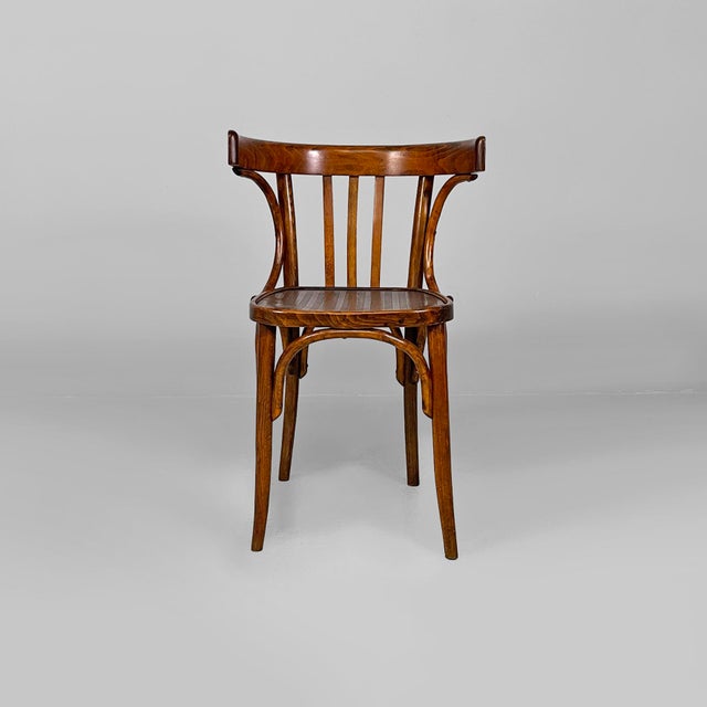 Set of four chairs in wood. The backrest and armrests are composed of curved wooden slats. Round-section legs. 1940s. Good...