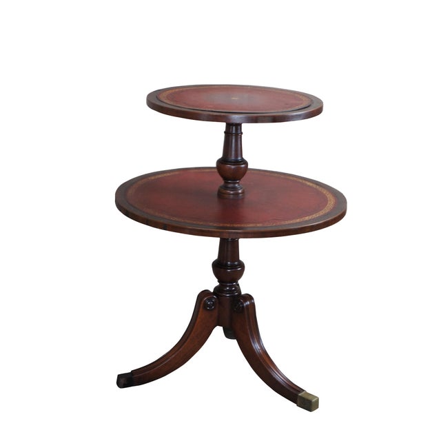 A quaint mid century Regency style dumbwaiter table. Made from mahogany with two tiered tooled red leather top. Features...