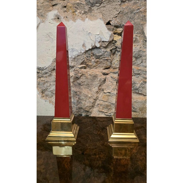 Pair of decorative obelisks in red-tinted resin, mounted on a profiled brass base. Purchased in 1990 from Jacques...