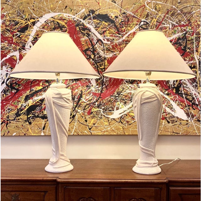 An elegant pair of 1970s sculptural John Dickinson style plaster pair of lamps in an ivory cream color. These Hollywood...