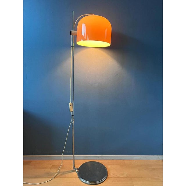 A very rare guzzini forma floor lamp featuring a striking orange shade that can be moved and positioned to direct the...