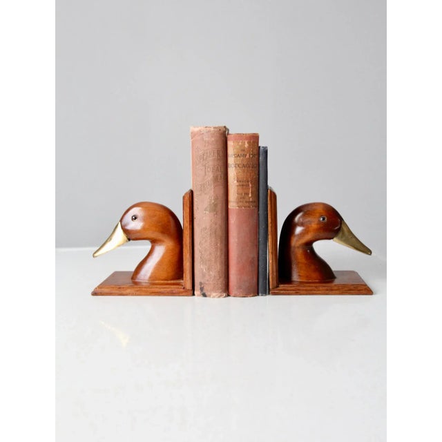 Pair of vintage duck bookends crafted from warm-toned wood and polished brass. This classic bookend set features...