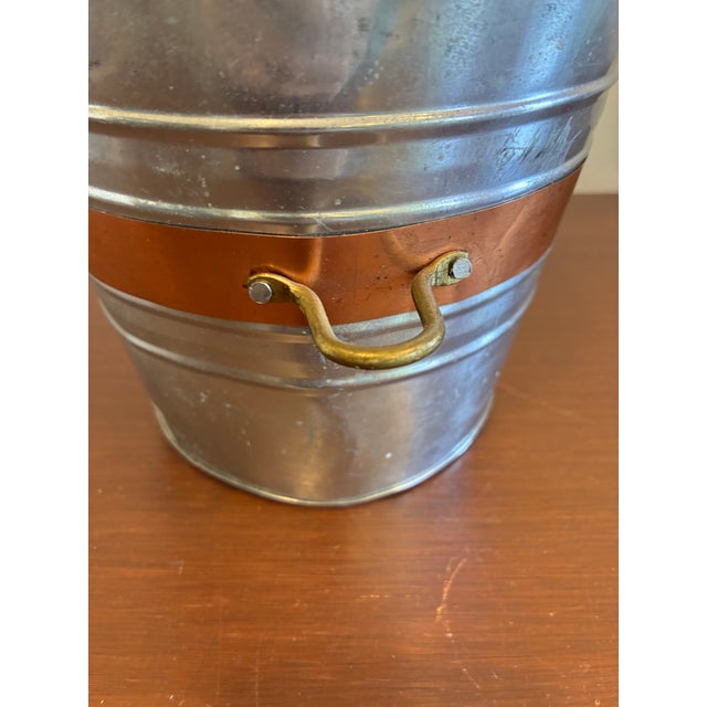 Vintage metal bucket made in India featuring a galvanized finish with a contrasting copper-tone accent band and brass side...