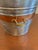 Vintage metal bucket made in India featuring a galvanized finish with a contrasting copper-tone accent band and brass side...