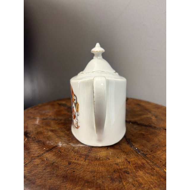 An antique English teapot commemorating the coronation of King George V and Queen Mary, richly adorned with colorful...