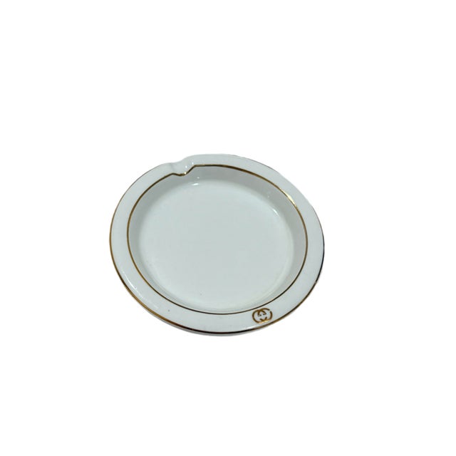 Vintage Gucci porcelain ashtray featuring gold-tone logo branding. Classic house design with clean white ceramic...