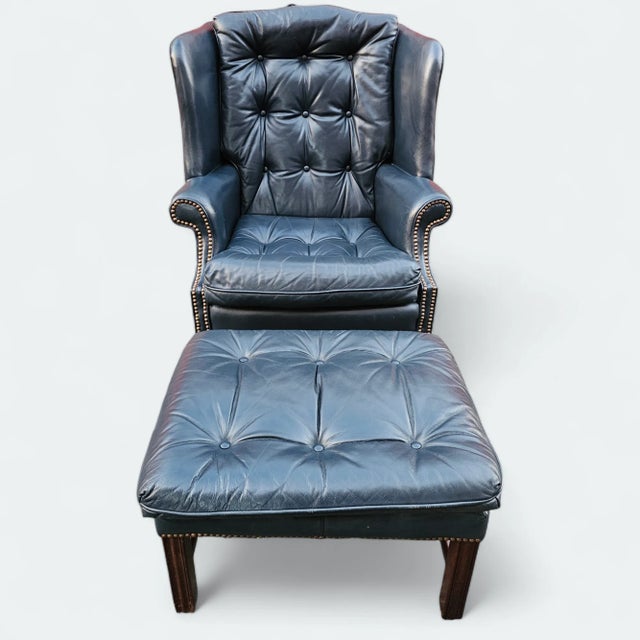 This Vintage Blue Tufted Leather Wing Chair and Ottoman by Classic Leather has a classic design and is constructed from a...
