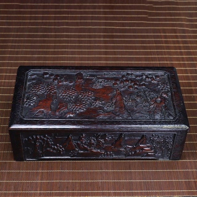 This is an exquisitely crafted rectangular wooden box, featuring intricate, deep relief carving across its surfaces....
