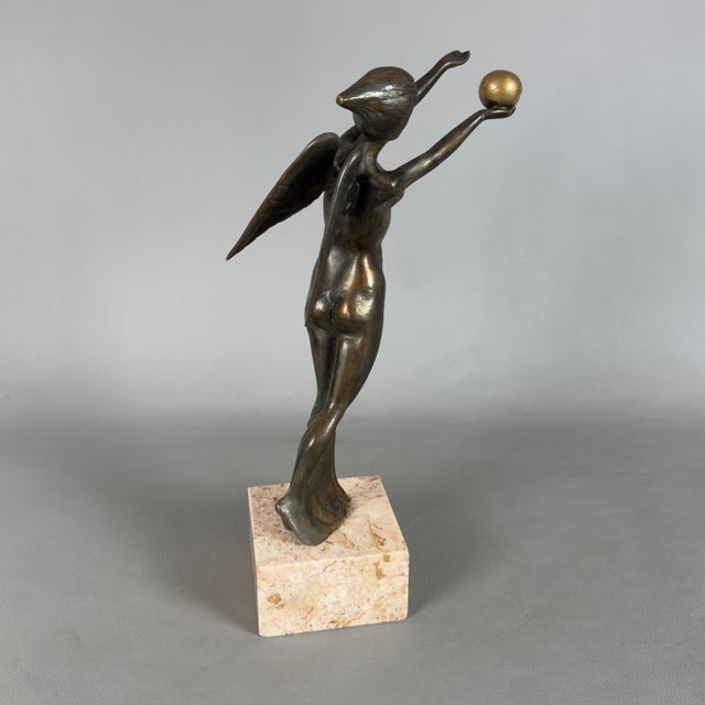 A slender freestanding figurative sculpture depicting Winged Victory (Nike), attributed to 20th-century craftsmanship....