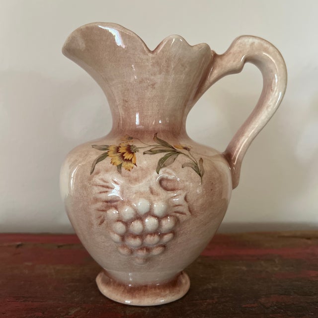 Vintage Grape Embossed Pitcher Featuring Florals with Scrolled Rim Based in unmarked; it may be Italian pottery. Measures...