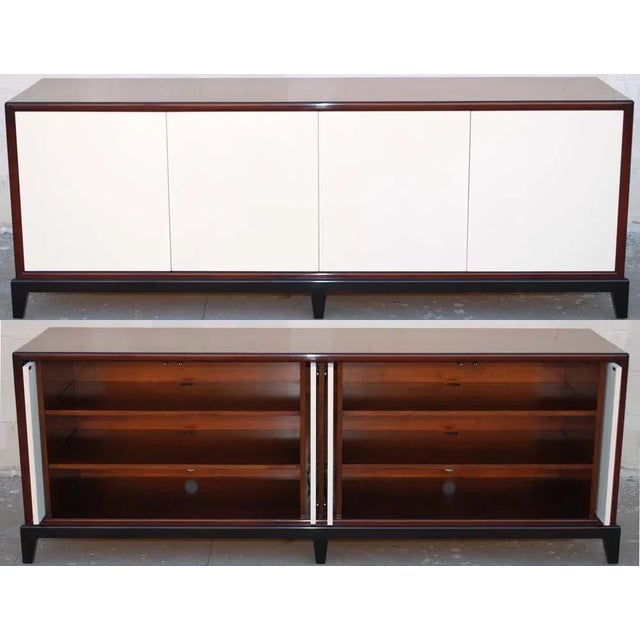 Sideboard with four pocket doors revealing two compartments and adjustable shelves. The finish is a rich walnut with an...