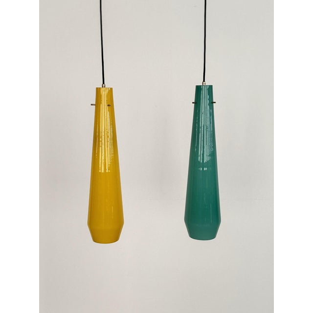 Beautiful pair of two XL glass pendant lights in different, shiny colors: petrol-green and yellow, inside the glasses is a...