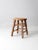 This is a vintage wooden stool. The painted brown wooden low height stool features a round seat with blocky wood legs and...