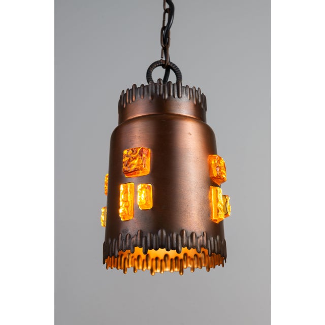 Great pair of brutalist mid-century brass pendants with adjustable chains. Shades are brass and filled with amber glass...