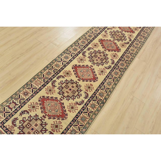 A tribal Caucasian Kazak runner hand-knotted with fine wool on a cotton foundation. This rug features a row of geometric...