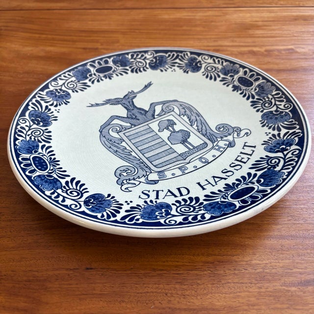 Rare Dutch Delft coat of arms wall plate, featuring a deer holding two acanthus leaves above a ribbon with the letters...