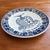 Rare Dutch Delft coat of arms wall plate, featuring a deer holding two acanthus leaves above a ribbon with the letters...