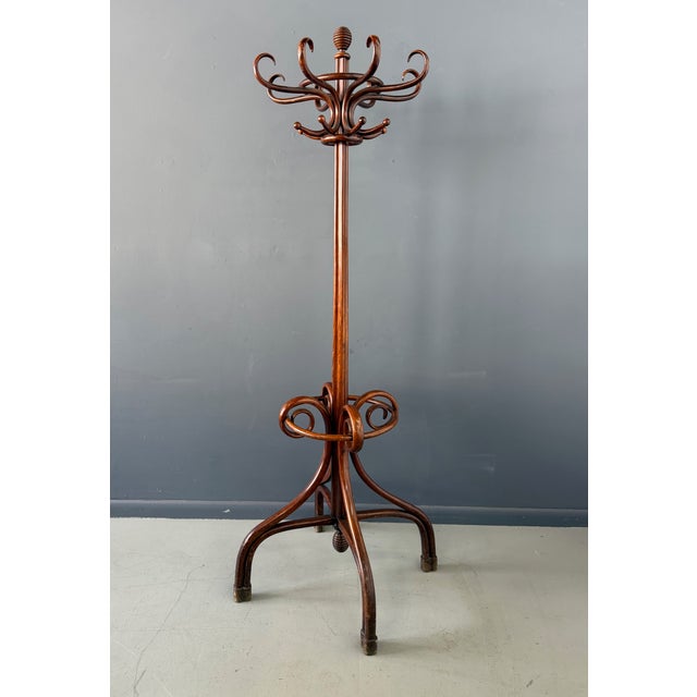 An elegant bentwood standing coat rack by Thonet, showcasing the firm’s mastery of steam-bent beechwood construction. The...