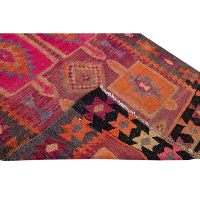 Beautiful kilim handmade wool runner with a pink field. This Vintage flatweave rug has orange, gray, and brown accents...