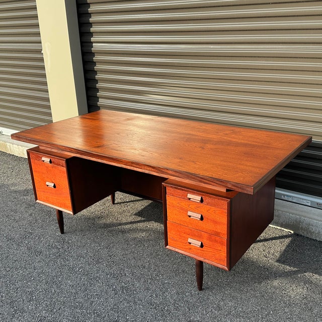 Sit down and start that novel you’ve been meaning to write. This vintage teak executive desk features a floating top, four...