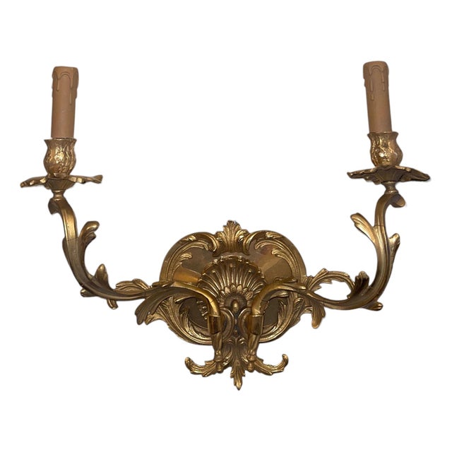 An elegant pair of French gilt bronze two-light wall sconces crafted in the Louis XV style during the 20th century. Richly...