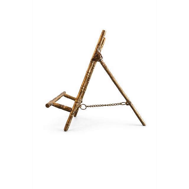 A charming vintage tabletop display easel crafted in a sculptural faux bamboo brass design, perfect for showcasing a small...