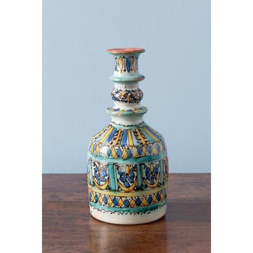 A late 19th-century Moroccan pottery bottle from Fez. The form is sculptural, with a wide lower body tapering to a ringed...
