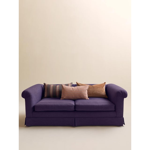 This loveseat features a softly curved silhouette with rolled arms, a tailored skirt, and deep plum linen upholstery that...