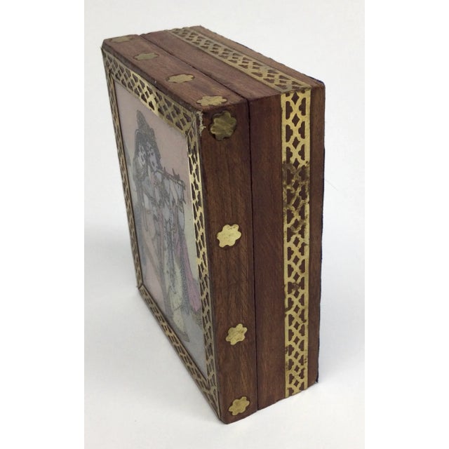 Hand painted under glass artwork of Indian couple decorates this wood hinged box with delicate brass work and inlays. I...