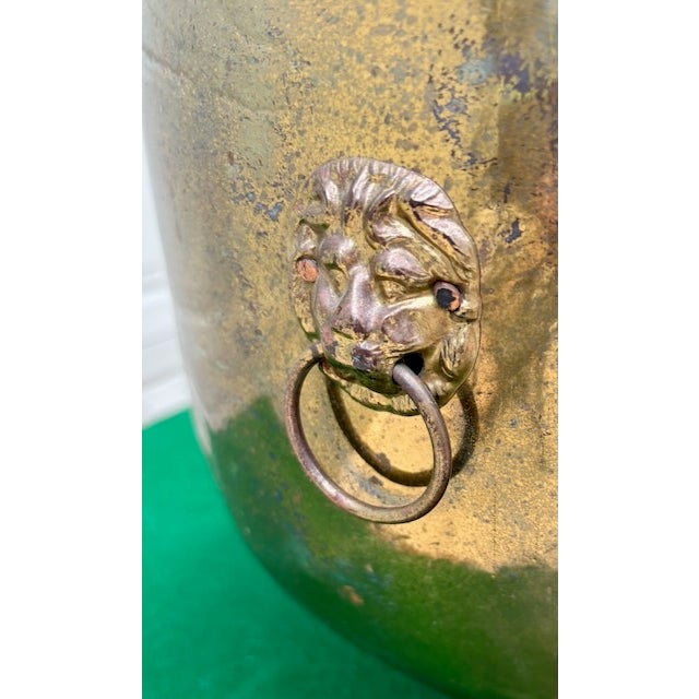 Large antique brass English cachepot with ornate ring handles held by lion heads and tripod feet shaped like lion paws....