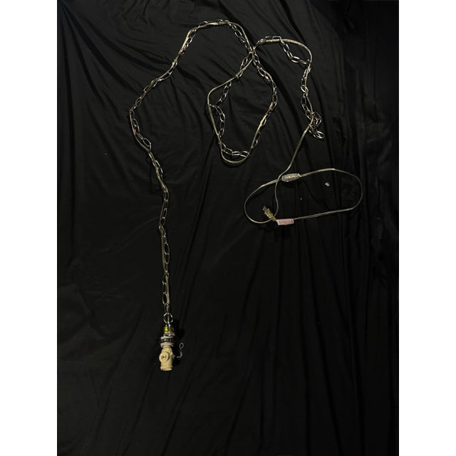 A versatile plug-in swag pendant light with a long hanging chain and pull-chain socket, offering a clean blend of...