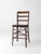 An antique early 20th century chair with a riveted metal frame and wood plank seat. The tall ladder back and gracefully...